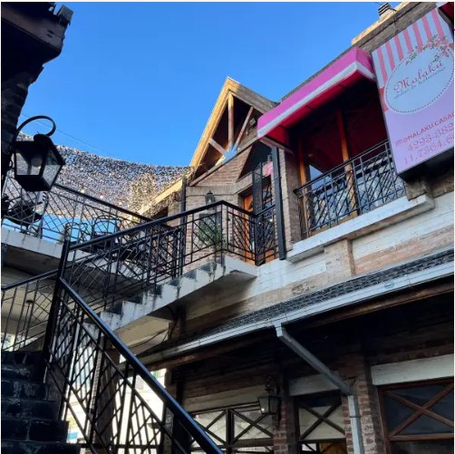 El local de Malaku en Adrogué: un primer piso con balcón y toldo rosa, al que se sube por una escalera
